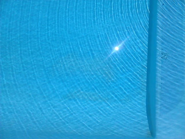 odraz slunce na modré hladině bazénu